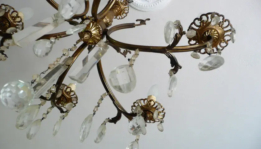 Un vecchio lampadario in ottone con pendenti di cristallo, un'idea per come riutilizzare un vecchio lampadario.