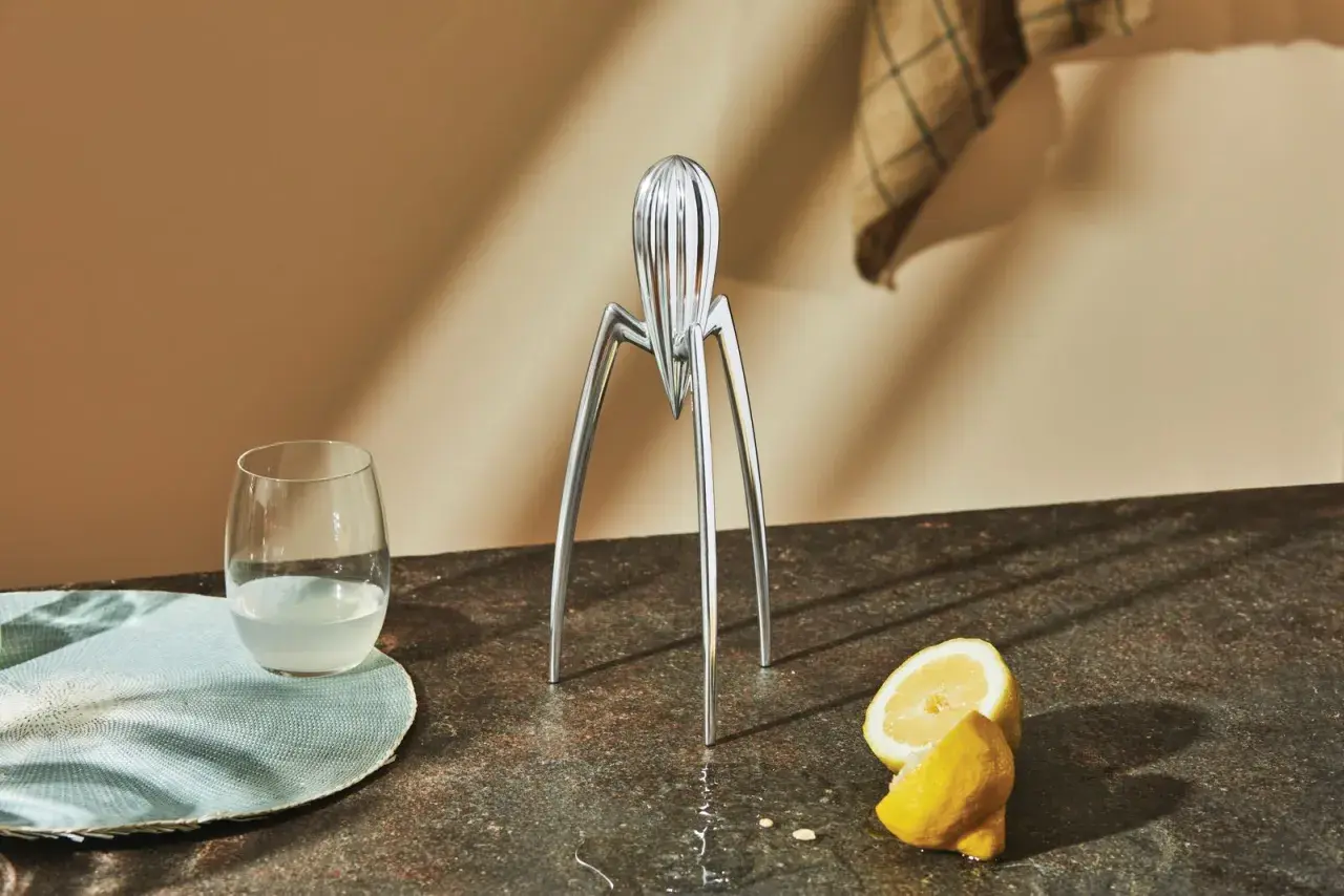 Spremiagrumi iconico di Philippe Starck, un bicchiere di succo e limoni freschi su un piano di lavoro.