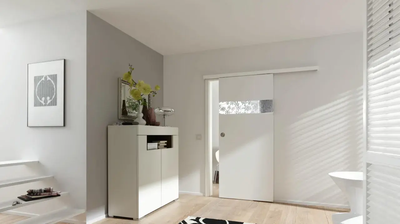 Una moderna porta scorrevole bianca con inserto decorato, perfetta per costruire una porta scorrevole in un ingresso luminoso.