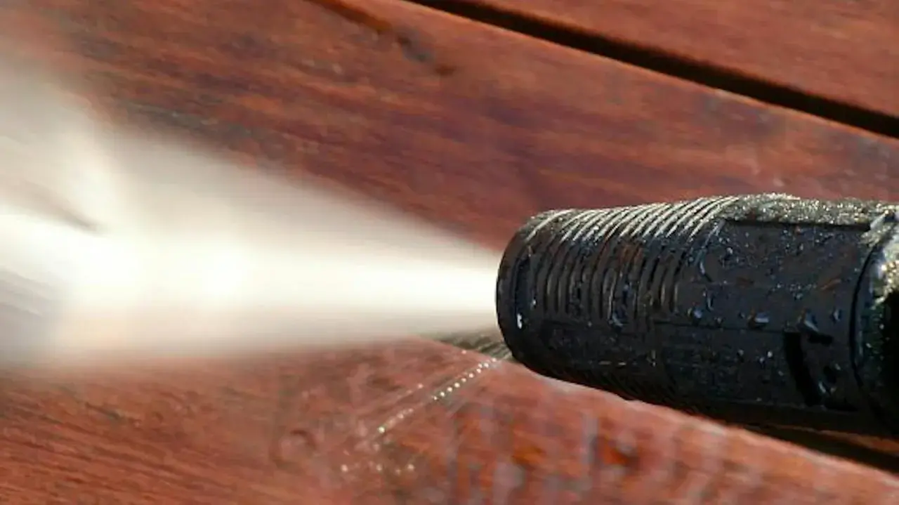 Ugello idropulitrice spruzza acqua su un deck in legno per eliminare odore vernice legno.