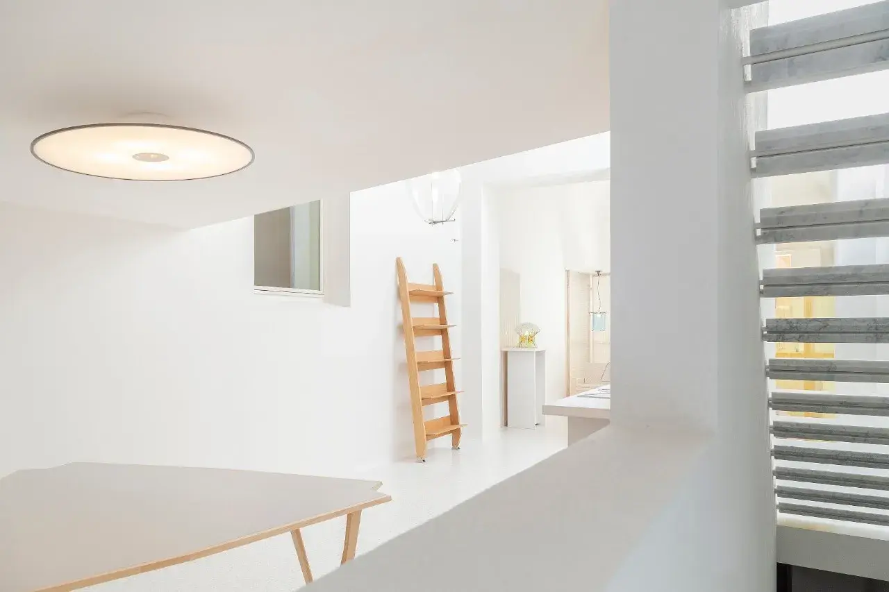 Interni luminosi con tavolo, scala in legno e lampada Umberto Riva.