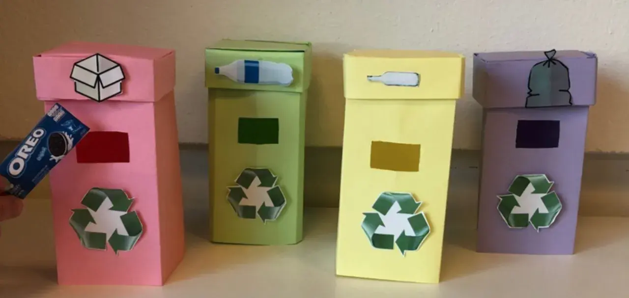 Quattro colorati contenitori per la raccolta differenziata fai da te, con simboli e immagini che indicano cosa gettare.