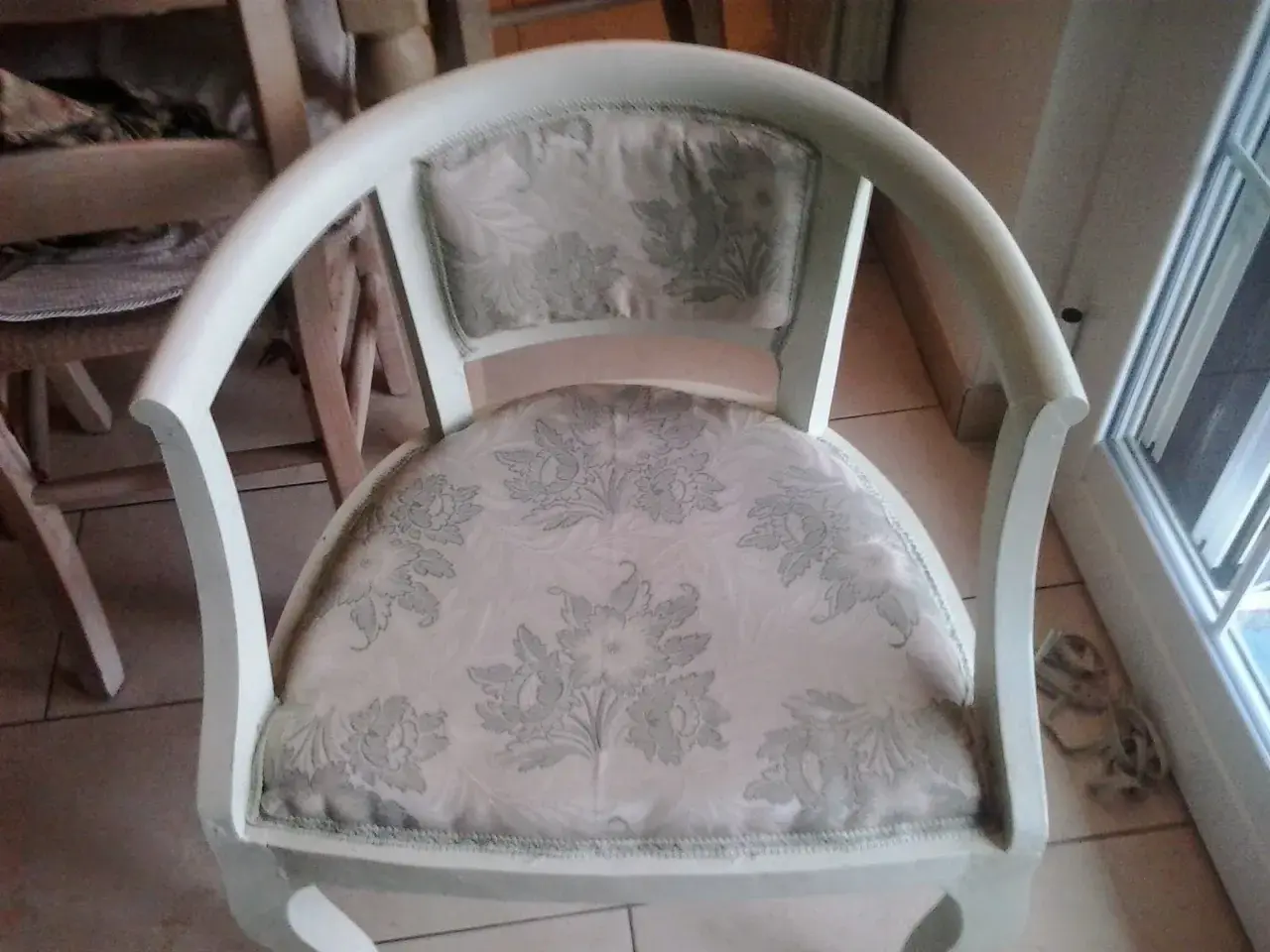 Vecchia poltrona in attesa di un restyling shabby chic. Tessuto floreale chiaro e struttura bianca da rinnovare.