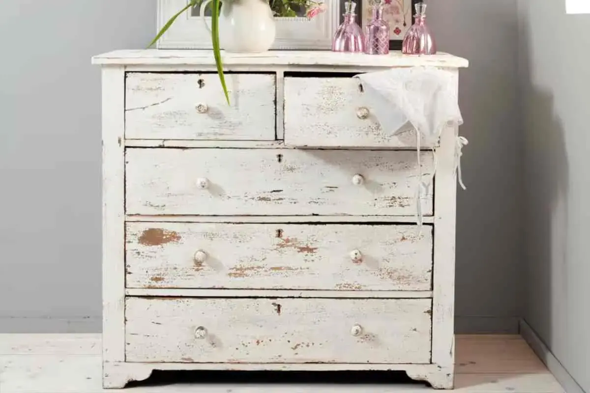 Cassettiera bianca con finitura invecchiata, tipica della tecnica shabby. Dettagli consumati e pomelli in ceramica.