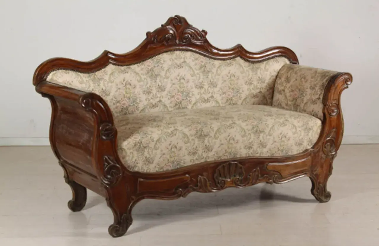 Divano in legno intagliato, con tessuto floreale, in **stile Luigi Filippo**. Un pezzo d'antiquariato che evoca eleganza.