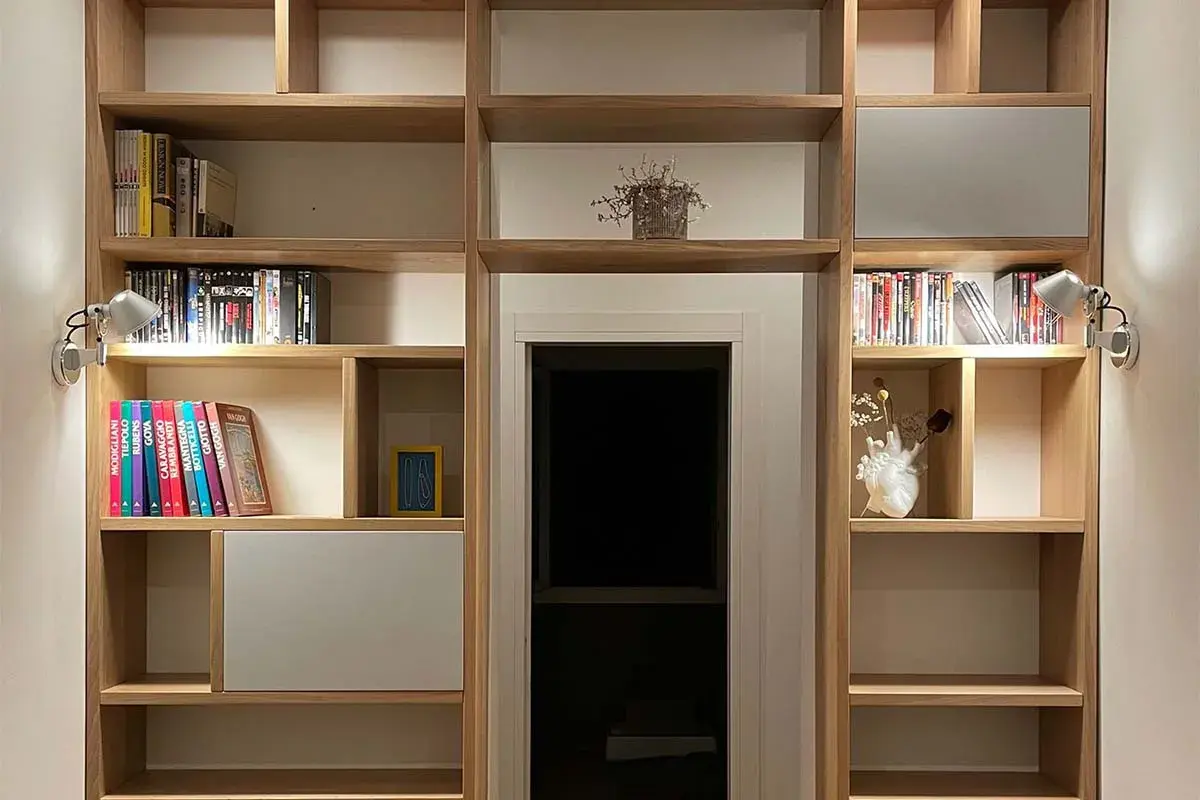 Libreria in legno con libri, vasi e faretti. Un'idea per costruire una libreria funzionale e di design.