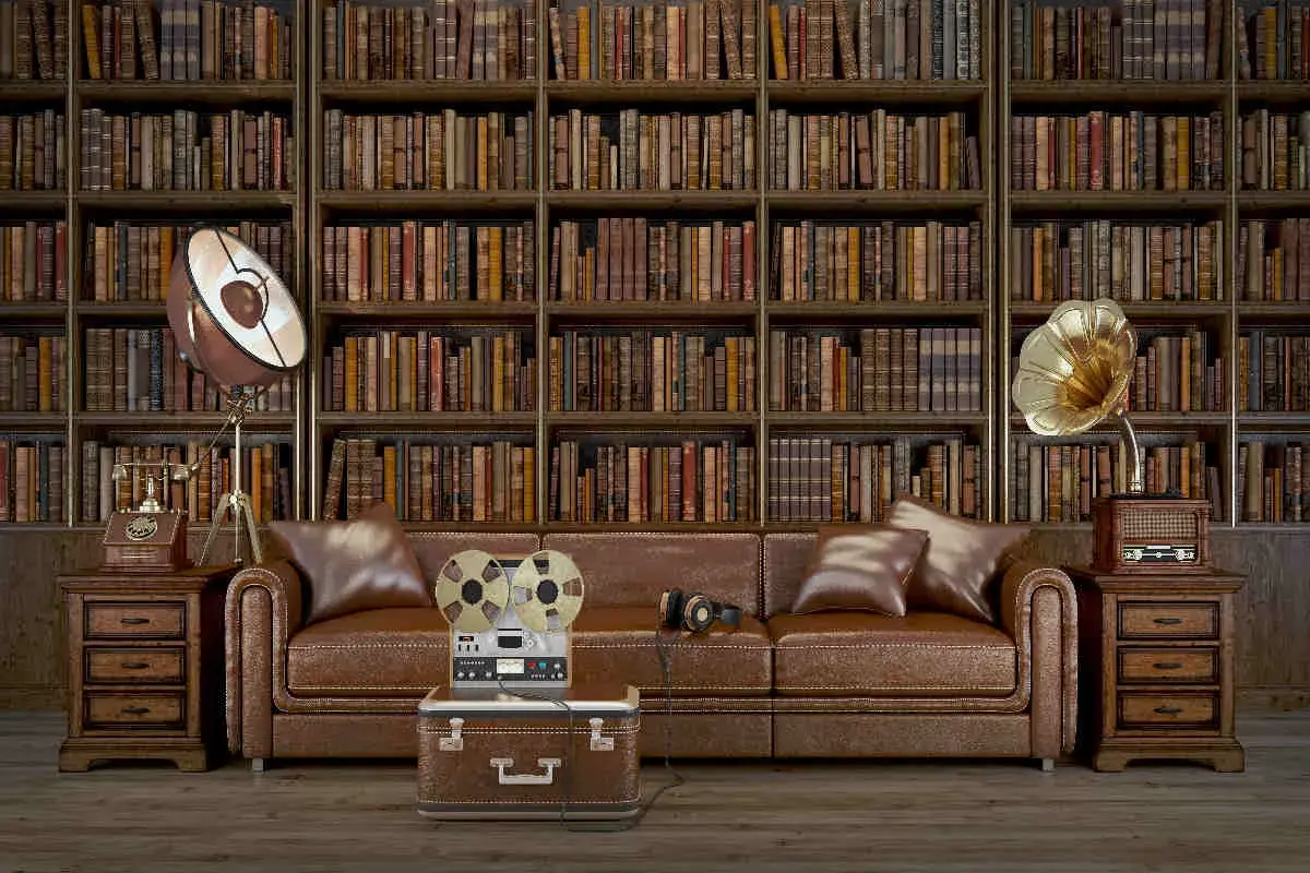 Un salotto in stile dark academia con divano in pelle, libreria imponente e oggetti vintage come un giradischi e un registratore a bobine.