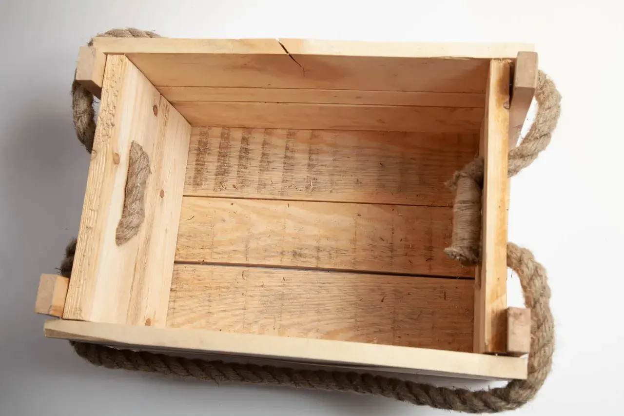 Una cassetta in legno grezzo con manici in corda, perfetta per chi vuole imparare come costruire una cassetta in legno.
