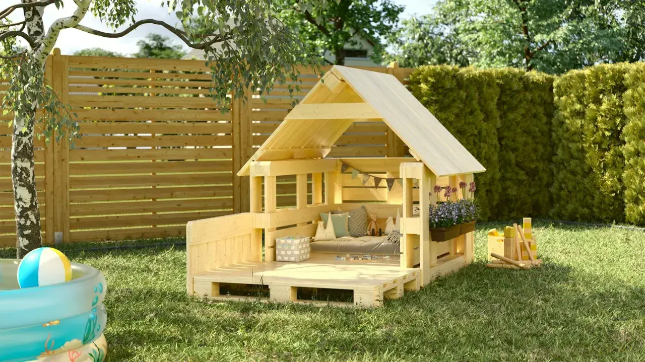 Una capanna per bambini fai da te in legno, con cuscini, fiori e giochi, pronta per l'avventura in giardino.