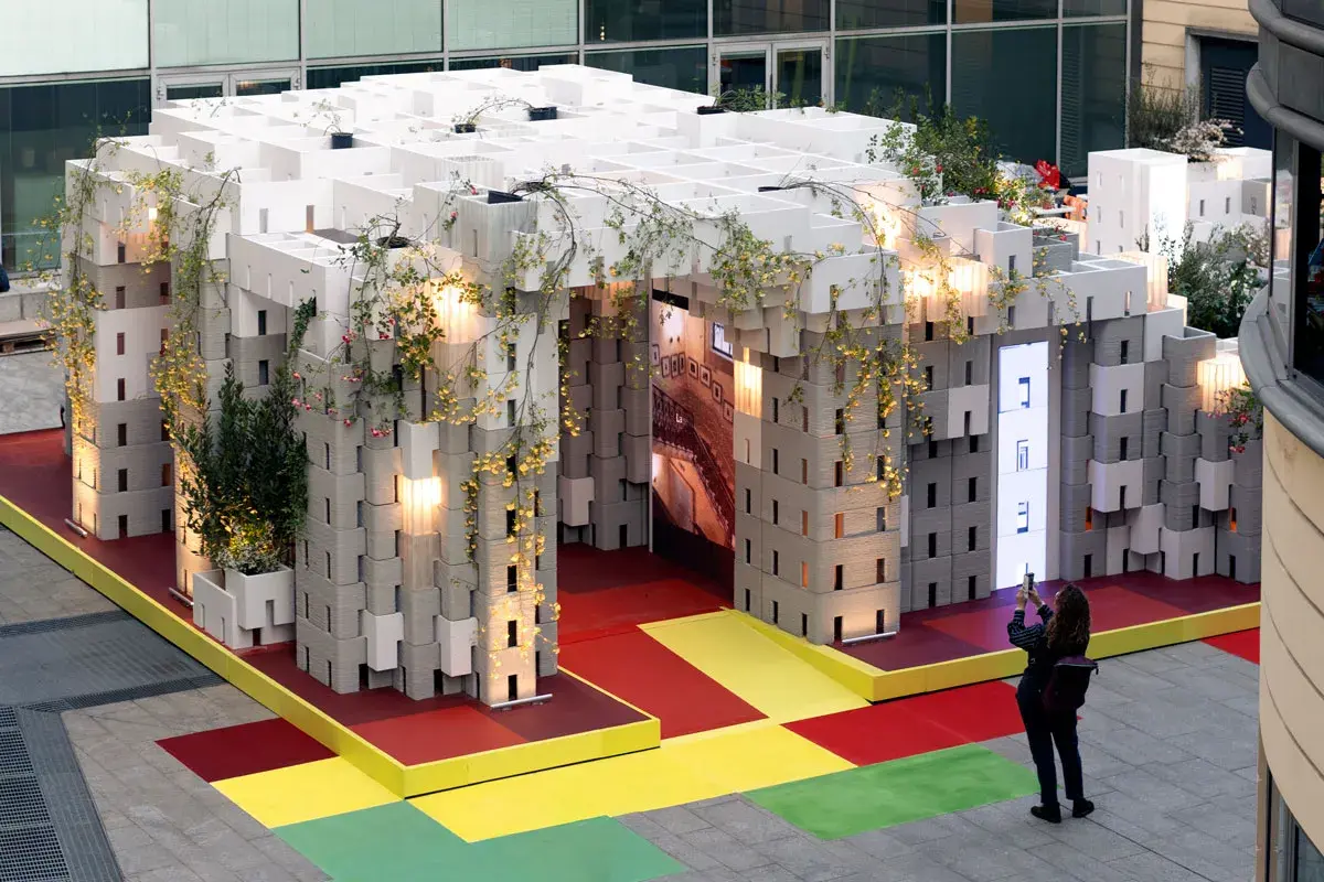 Installazione modulare con piante rampicanti, un'anticipazione della design week milano 2026. Una persona scatta una foto.