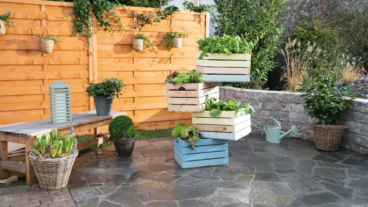 Fioriera fai da te con cassette di legno colorate impilate, piene di verdure fresche. Un'idea creativa per il tuo orto.