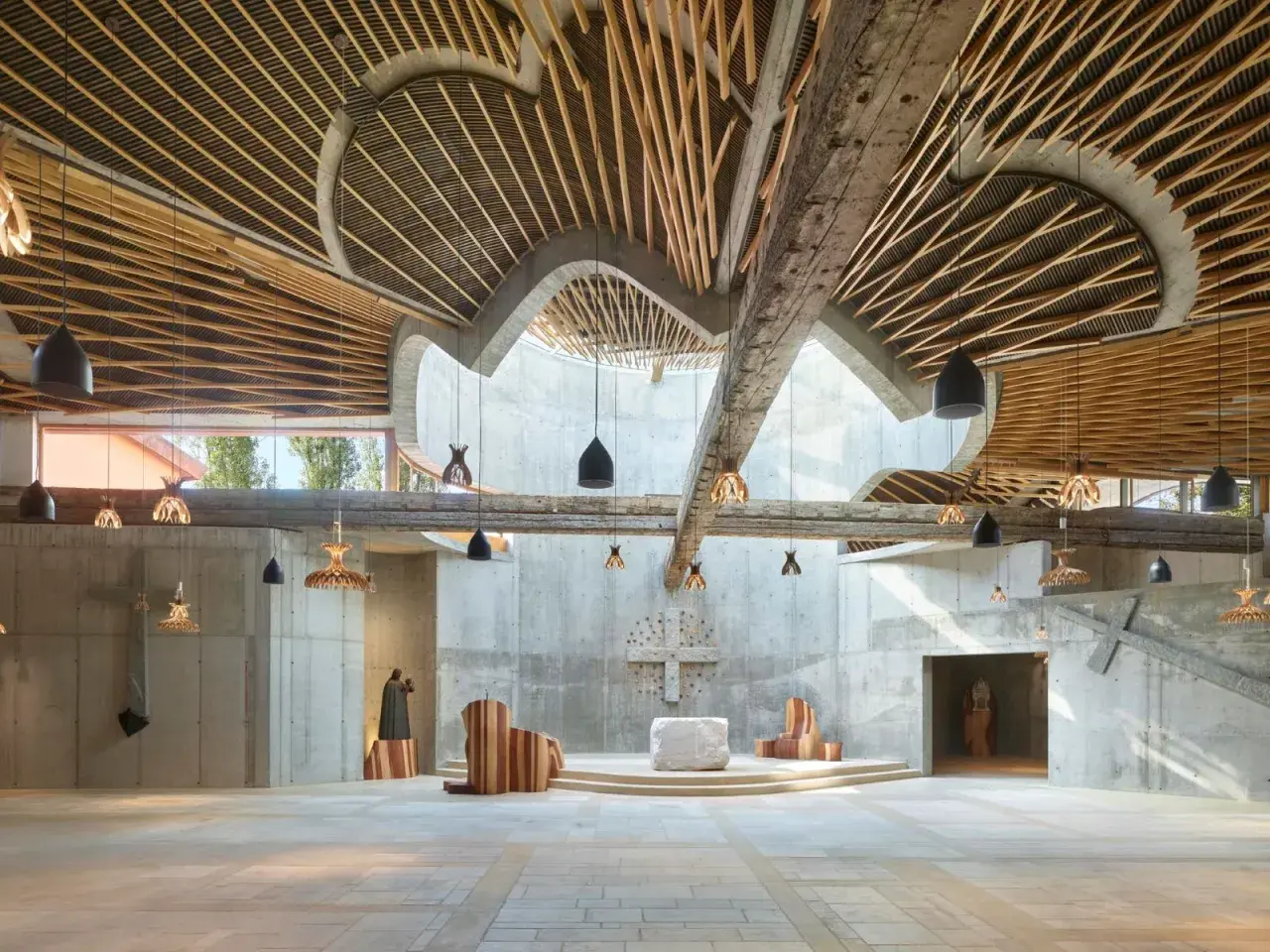Interno di chiesa moderna con soffitto in legno e cemento, opera di Benedetta Tagliabue.