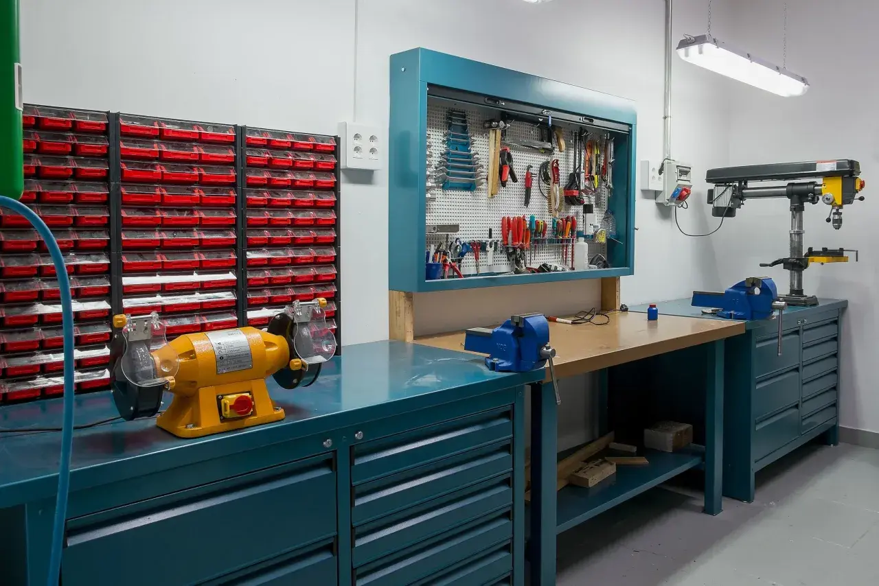 Un'officina ben organizzata con morsa, trapano a colonna, mola e tanti cassetti per idee officina fai da te.