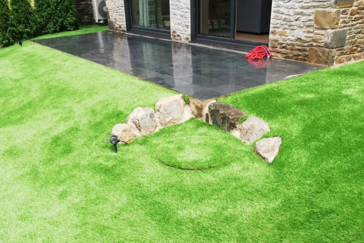 Prato sintetico su terra: un'area verde brillante con pietre decorative e un impianto di irrigazione.