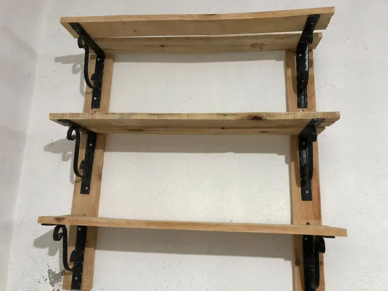 Scaffali in legno fai da te, con staffe nere decorative, perfetti per un tocco rustico.