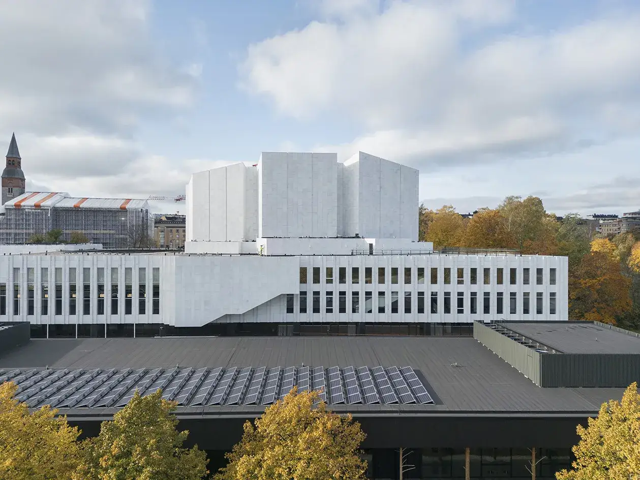 Edificio moderno in marmo bianco, un esempio delle alvar aalto opere, con pannelli solari sul tetto e alberi autunnali circostanti.