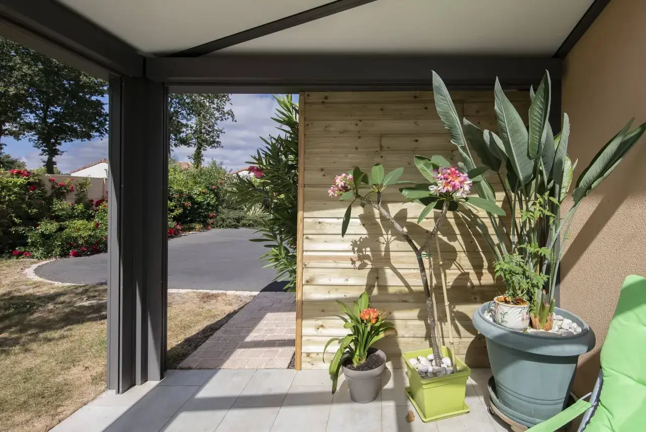 Un angolo relax con piante rigogliose sotto una moderna pergola fai da te legno. L'esterno invita con fiori e verde.