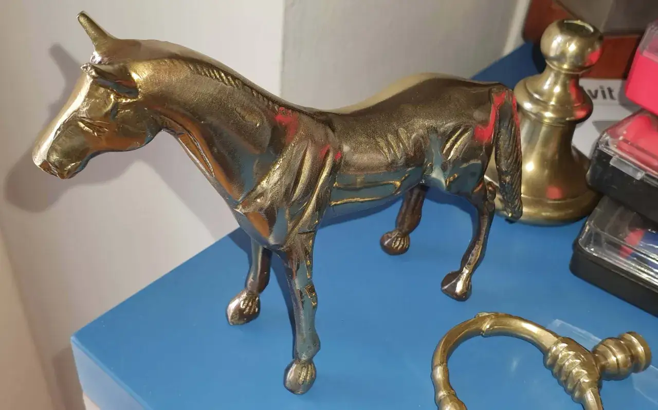 Statuetta di cavallo in bronzo lucido, con riflessi rossastri e dorati, che mostra i segni del tempo mentre il bronzo si ossida.