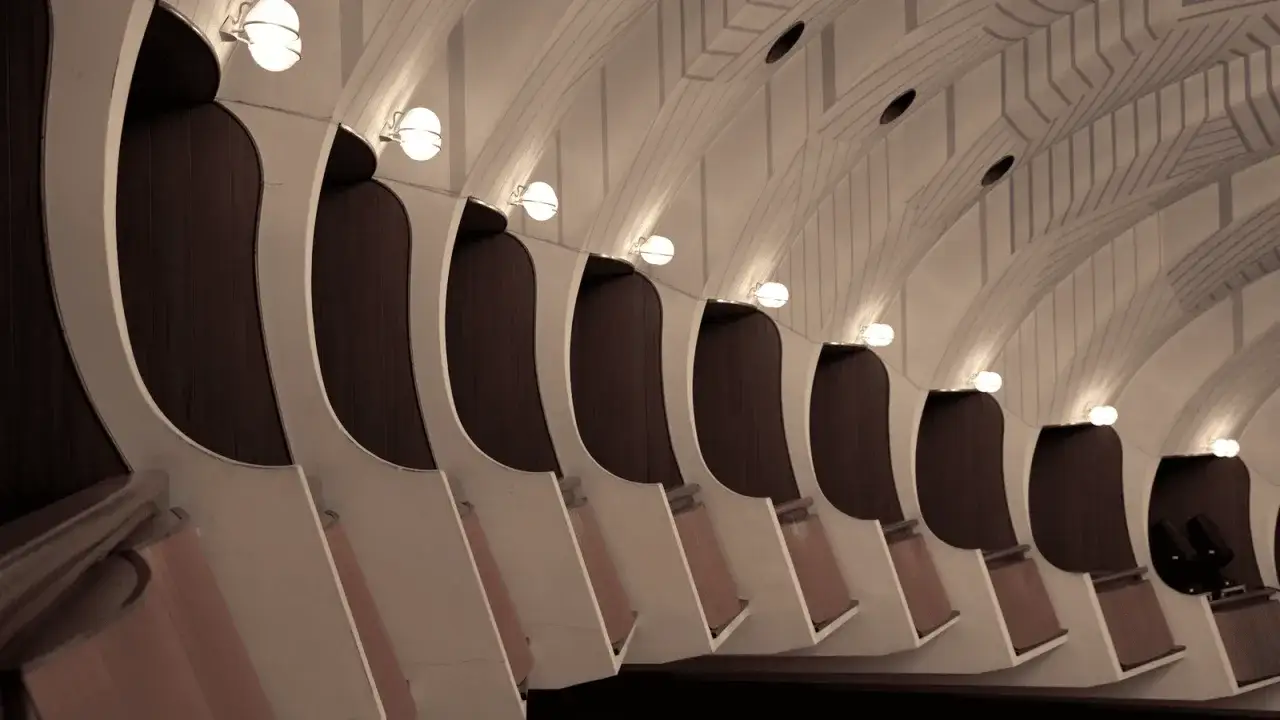 Sedili curvi e illuminazione soffusa in un ambiente che evoca il design di Carlo Mollino.
