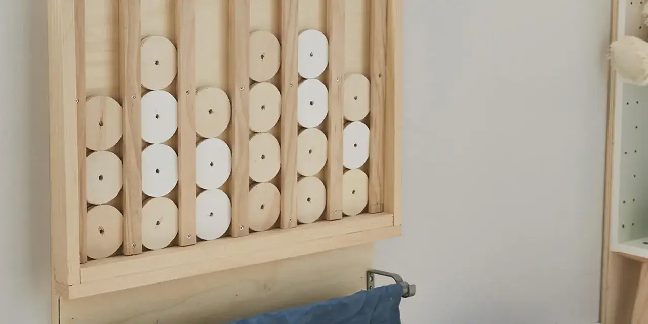 Un gioco da tavolo fai da te in legno, con dischi bianchi e naturali che scorrono su binari verticali.