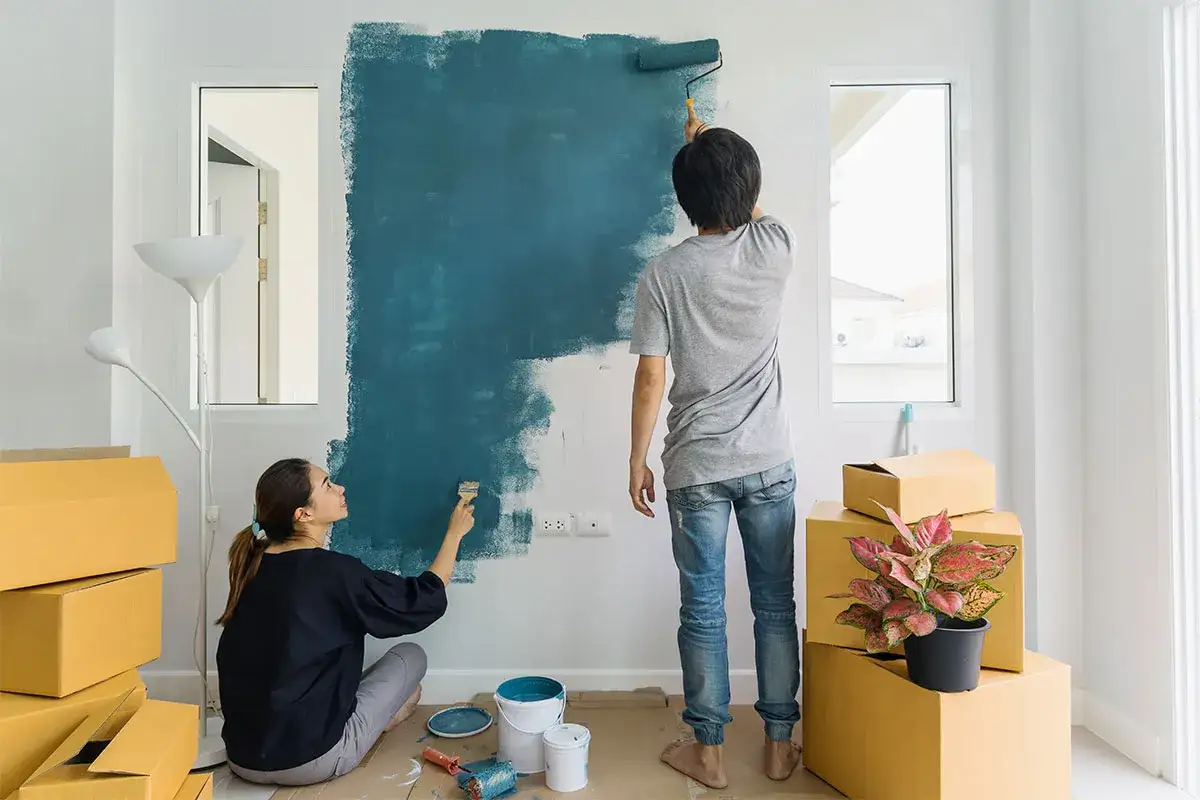 Coppia impegnata nel pitturare casa fai da te, trasformando un muro con un vivace colore blu.