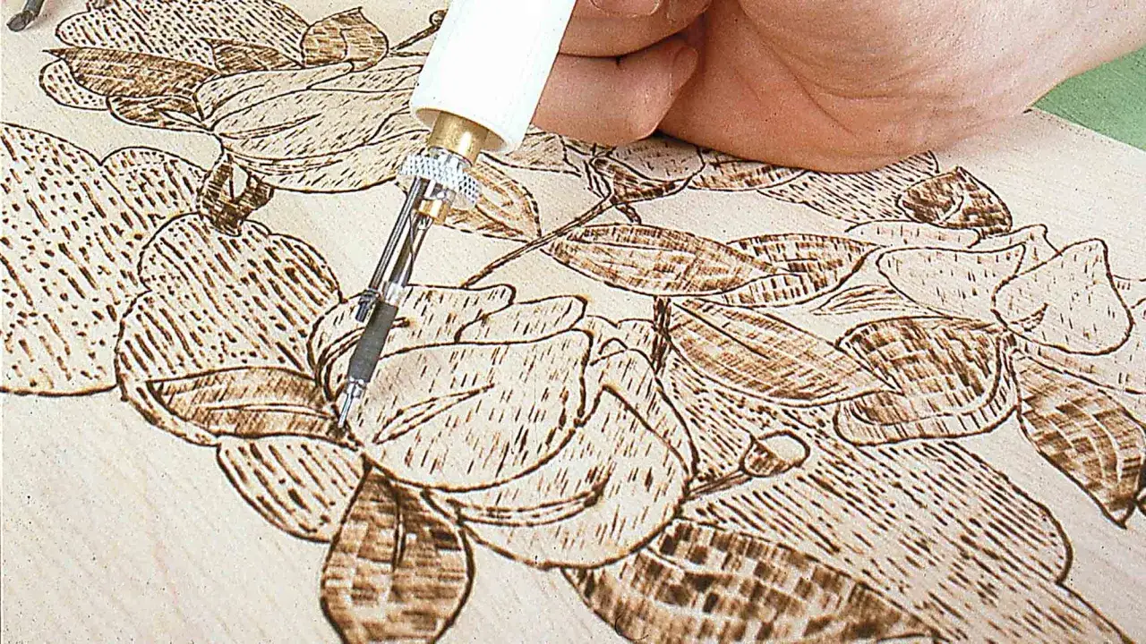 Mano che usa uno strumento per incidere un disegno floreale su legno, mostrando come disegnare sul legno con dettagli intricati.