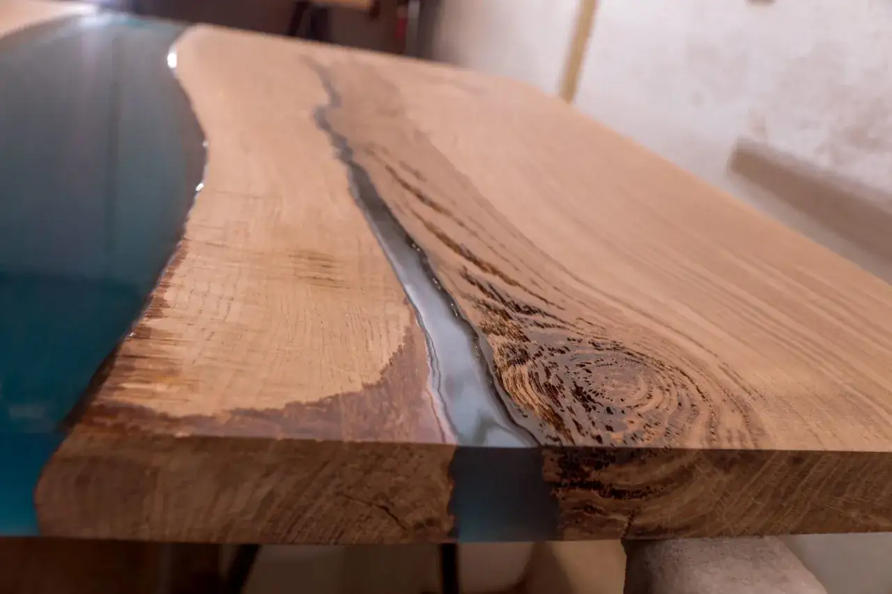 Un tavolo in legno con un fiume di resina epossidica blu che scorre tra le venature. Ecco come usare la resina epossidica sul legno per creare effetti unici.