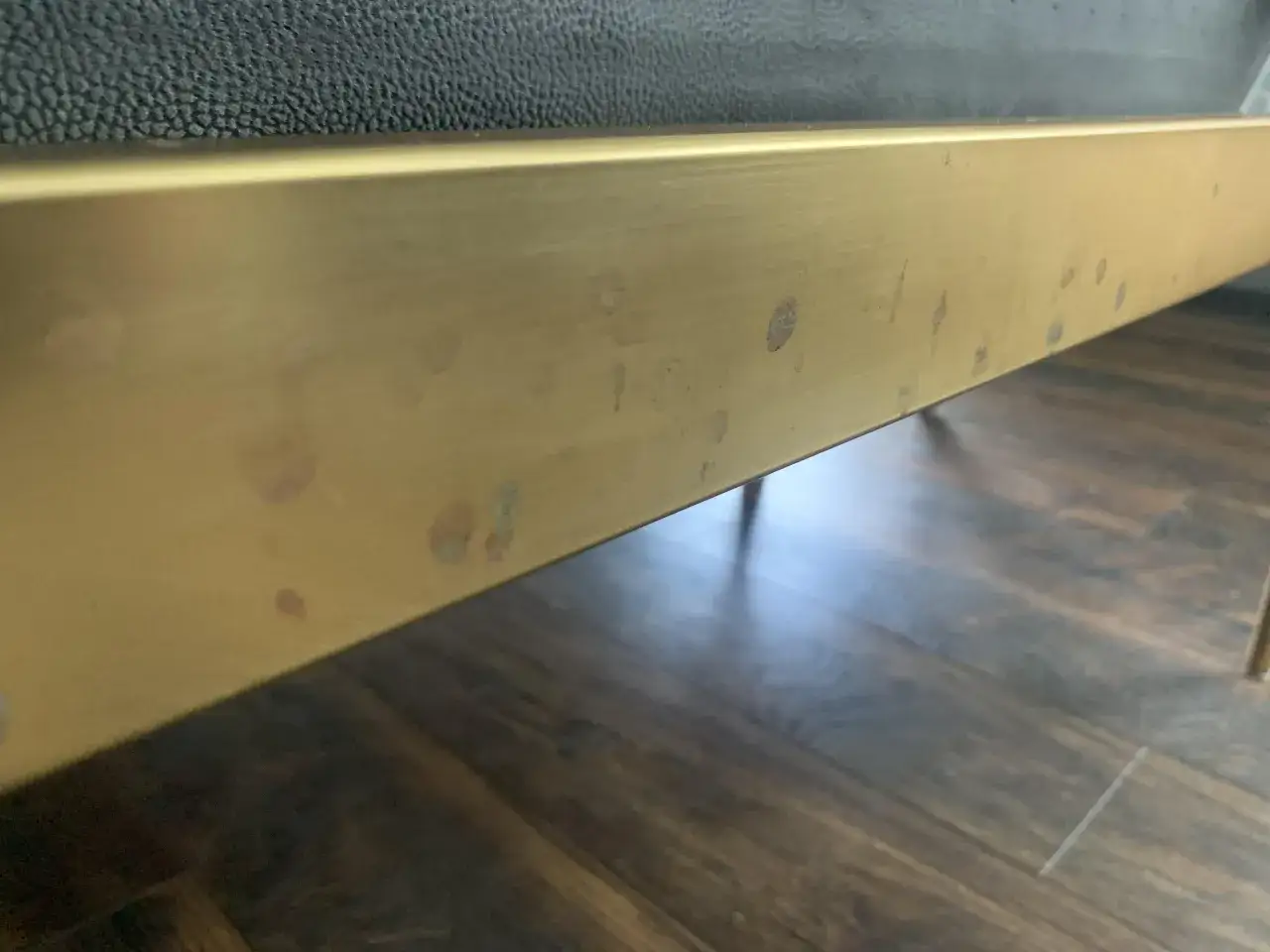 Dettaglio di un bordo di un letto con finitura in ottone ossidato, macchie evidenti che necessitano di pulizia.